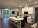 Bright kitchen featuring modern white cabinets, stainless steel appliances, and a large island with bar stools at 159 Wood Orchid Ln, Garner, NC 27529