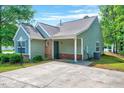 Well-maintained home with green siding, a side driveway, and mature trees around the property at 2 Donnelly Ct, Durham, NC 27713