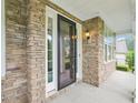 Inviting covered front porch with a stone facade, exterior lighting, and black framed glass storm door at 203 S South Bend Dr, Durham, NC 27713
