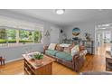 Cozy living room featuring hardwood floors, a leather couch, and a large window overlooking the yard at 2125 Cheek Rd, Durham, NC 27704