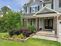 Inviting covered front porch with stone accents and comfortable seating, perfect for relaxing outdoors at 213 Lofty Oak Ln, Holly Springs, NC 27540