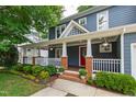 Charming covered front porch with brick columns, white railings, and a beautiful landscaped garden at 2309 Filigree Ct, Raleigh, NC 27614