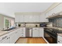 Bright kitchen features white cabinets, granite countertops, stainless steel appliances and hardwood floors at 5513 Doemont Dr, Apex, NC 27539