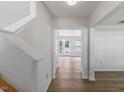 Bright foyer area with wood-look floors, white walls, a view of the staircase, and a doorway at 5940 Brambleton Ave, Raleigh, NC 27610