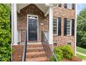 Close up of the brick front porch with a black door and traditional details at 601 Culpepper Ct, Durham, NC 27712