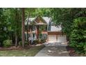 Two-story brick home featuring a two-car garage and manicured landscaping, set among mature trees at 104 Tutbury Pl, Cary, NC 27519