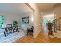 Open hallway leading to a bright office with a wooden desk and hardwood floors at 104 Tutbury Pl, Cary, NC 27519