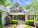 A beautiful brick and stone home with a manicured lawn, lush greenery, and an inviting entryway at 10540 Byrum Woods Dr, Raleigh, NC 27613