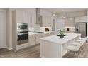 Bright kitchen with white cabinets, stainless steel appliances, modern lighting, and a kitchen island with seating at 1105 Masters Place Way # 154, Durham, NC 27703