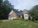 Beautiful two story brick home featuring an attached two car garage and mature trees in the yard at 11221 Paddy Hollow Ln, Raleigh, NC 27614