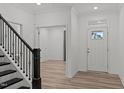 Inviting foyer with a staircase featuring dark wooden bannisters and light wood-look flooring at 125 Shadowdale Ln, Rolesville, NC 27571