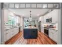 Bright kitchen features white cabinets, stainless appliances, and a center island with granite countertops at 129 E Chestnut Ave, Wake Forest, NC 27587