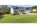 Inviting one-story home with manicured lawn, white porch, flower beds, and attached two-car garage at 174 Tafton Dr, Wendell, NC 27591