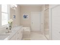 Bright bathroom featuring double sinks, a soaking tub, a glass-enclosed shower and neutral tile at 2000 Kapalua Way # 187, Durham, NC 27703