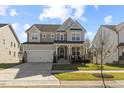 Inviting two-story home featuring a covered front porch and lush green lawn under a bright blue sky at 204 Woodstaff Ave, Wake Forest, NC 27587