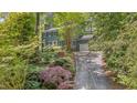 View of a lovely two-story home with lush landscaping, mature trees, and a private driveway at 207 Old Forest Creek Dr, Chapel Hill, NC 27514
