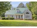Charming home with a well-manicured lawn, a welcoming porch, and a distinctive green metal roof at 213 Birch Creek Dr, Fuquay Varina, NC 27526