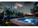 Inviting backyard pool area featuring a sparkling pool, string lights, palm trees, and patio umbrellas at 213 Birch Creek Dr, Fuquay Varina, NC 27526