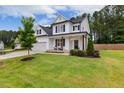 Beautiful white house with black shutters, a covered porch, green lawn and mature trees on a sunny day at 22 Chapman Ct, Wendell, NC 27591