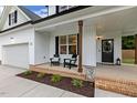 Inviting front porch with seating, brick accents, dark stained pillars, and stylish decor near the front door at 22 Chapman Ct, Wendell, NC 27591