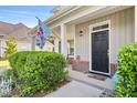 Inviting front entrance with black door, blooming shrubs, and attractive landscaping at 2207 Wimberly Woods Dr, Sanford, NC 27330
