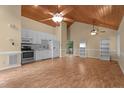 Open-concept living room with hardwood floors, light yellow walls, and vaulted wood ceiling into kitchen at 222 Sagamore Dr, Louisburg, NC 27549