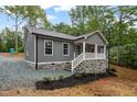 Cozy one-story home featuring gray siding, a stone foundation, and a charming front porch with bright white railings at 249 Fisherman Point Rd, Roxboro, NC 27574