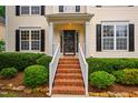 Close-up of the entrance and porch shows the brick steps and manicured bushes at 303 Laurens Way, Chapel Hill, NC 27516
