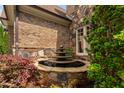 A beautiful stone fountain is nestled between brick and stone walls near the green landscaping at 3601 Nightfall Ct, Raleigh, NC 27607