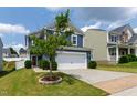 View of home with 2-car garage, blue siding, and a well-maintained lawn with a young tree at 3913 Massey Pointe Ct, Raleigh, NC 27616