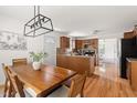 Open kitchen and dining area with wooden cabinets, island, hardwood floors, and modern lighting at 407 Sparella St, Durham, NC 27703