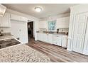 Open kitchen with stainless steel appliances, granite countertops, and white cabinets with updated flooring at 5401 Lower Creek Ct, Apex, NC 27539