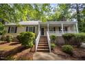 Inviting single Gathering home featuring a classic covered porch with brick base, complemented by lush greenery and brick stairs at 5804 Heatherbrook Cir, Raleigh, NC 27612