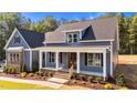Attractive exterior with blue siding, white trim, a welcoming porch, and beautifully maintained landscaping at 60 Stream View Way, Spring Hope, NC 27882
