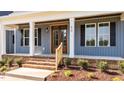 Close-up of a welcoming front porch with a wooden door, white columns, and neatly trimmed shrubs at 60 Stream View Way, Spring Hope, NC 27882