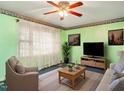 Cozy living room featuring bright green walls, a ceiling fan, and plush seating for a comfortable and inviting atmosphere at 605 Mace Rd, Mebane, NC 27302