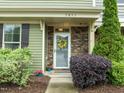 Close-up of the front door, featuring a decorative wreath, stone accents, and manicured landscaping at 7871 Allscott Way, Raleigh, NC 27612