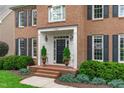 Elegant home entrance featuring manicured shrubbery, potted plants, and a covered front porch at 7929 Pine Timber Dr, Raleigh, NC 27613