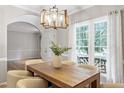 Inviting dining room with modern light fixture, large windows and wood table with seating for six at 9400 Leslieshire Dr, Raleigh, NC 27615