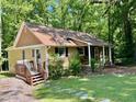 Backyard view of home with a wooden deck, lush lawn, and mature trees offering ample shade at 96 Holly Cir, Henderson, NC 27537