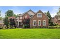 Stunning two-story brick home with a lush green lawn, mature trees, and manicured landscaping at 1010 Mill Pointe Way, Elon, NC 27244