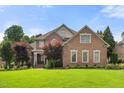 Imposing two-story brick home featuring manicured lawn, mature trees, and a well-maintained landscape at 1010 Mill Pointe Way, Elon, NC 27244