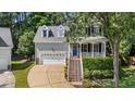 Charming two-story home with a welcoming front porch, dormer windows and an attached two car garage at 104 Kylesku Ct, Apex, NC 27502