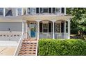 Inviting front porch with white columns, blue front door, and manicured landscaping at 104 Kylesku Ct, Apex, NC 27502