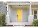 Inviting front porch with a striking yellow door and white columns enhance the curb appeal at 10744 Cokesbury Ln, Raleigh, NC 27614