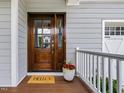 Elegant wood front door with glass panels, decorative plants, and a welcoming doormat at 1148 Tringham Ct, Apex, NC 27502