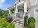 Inviting front porch with stone accents, white railings, and a wooden staircase at 1148 Tringham Ct, Apex, NC 27502
