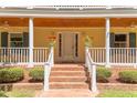 Inviting front porch with brick steps, white columns, and potted flowers, offering a warm welcome at 117 Carolina Forest Rd, Chapel Hill, NC 27516
