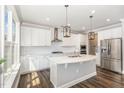 Modern white kitchen with stainless steel appliances, a large island with a sink, and designer pendant lighting at 2885 Farmhouse Dr, Apex, NC 27502