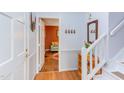 Bright foyer with hardwood floors, white wainscoting, stairs, and a view into a cozy room with a colorful accent wall at 520 Brittany Bay W, Raleigh, NC 27614
